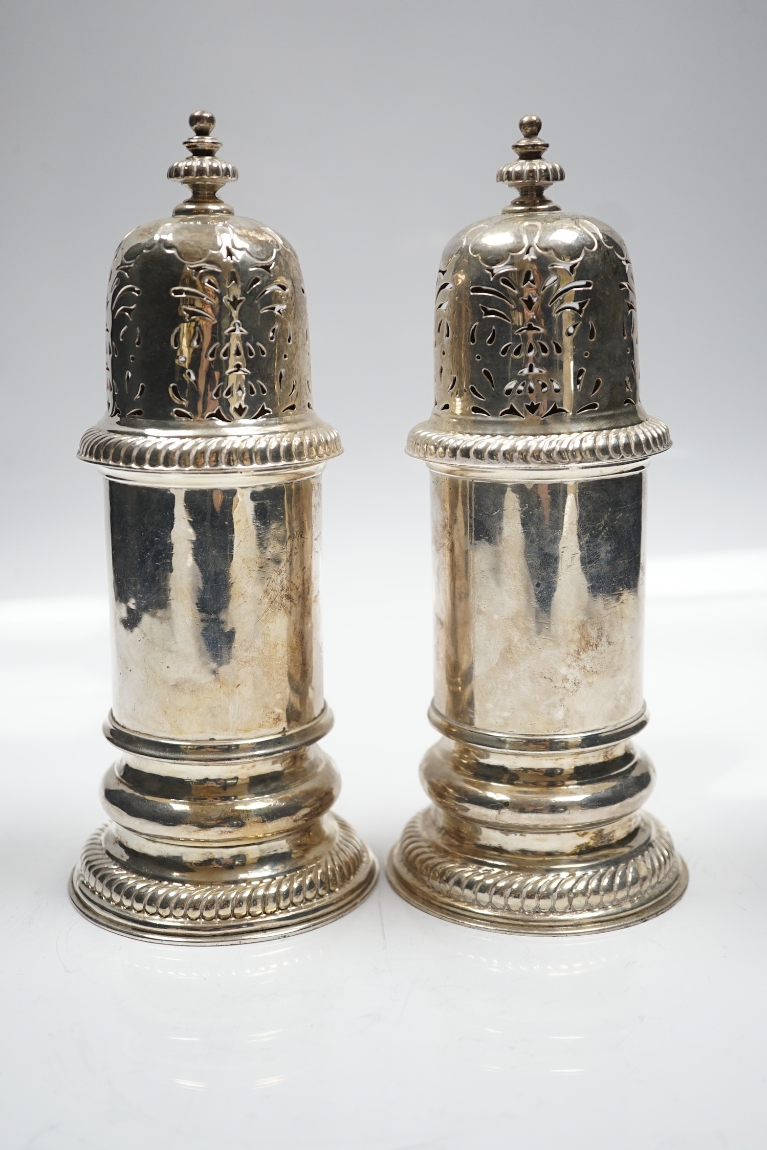 A matched pair of Britannia standard silver lighthouse sugar casters, Carrington & Co, London, 1903 and Wilson & Gill, London, 1963, 20.8cm, 22.6oz.